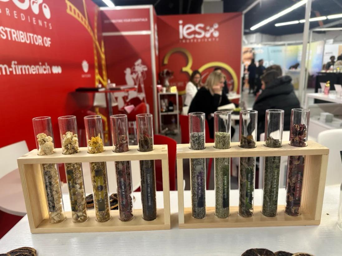 Tubes à essai contenant différents ingrédients naturels exposés sur stand IES Ingredients au salon professionnel