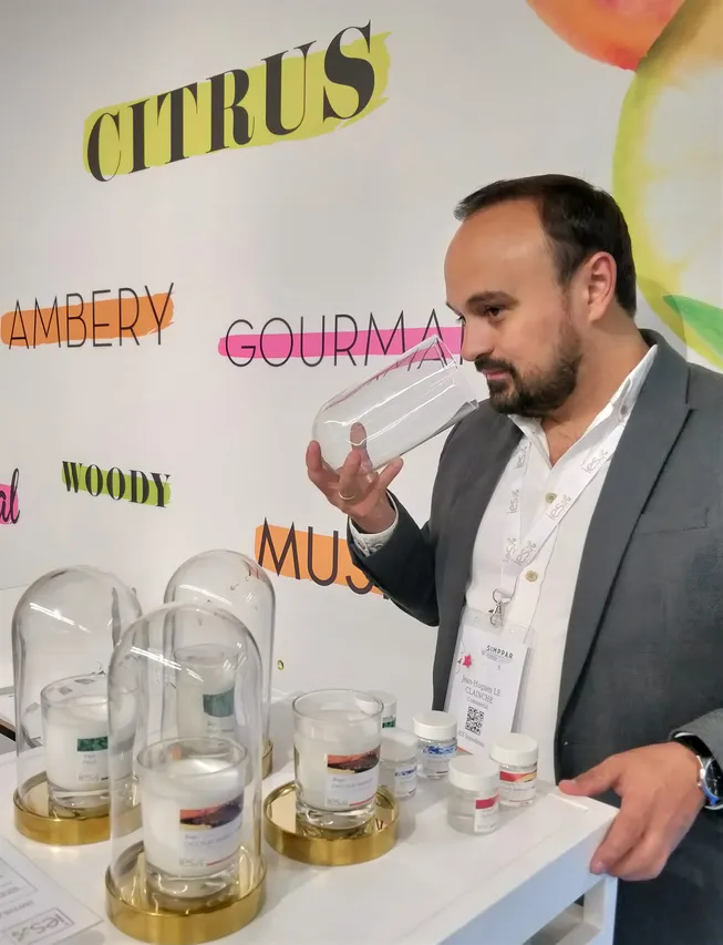 Man in suit presenting aroma samples under glass domes at a professional trade show
