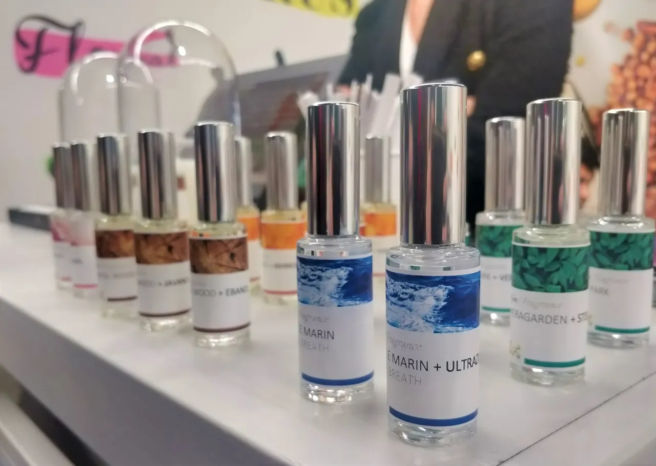 Collection of fragrance bottles with coloured caps arranged on a white display, natural ingredients
