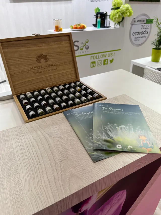 Open wooden box containing essential oil bottles with Be Organic brochures on a table