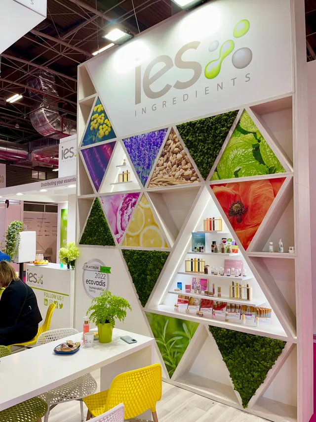 IES Ingredients stand at a professional trade show with a colorful hexagonal wall displaying natural cosmetics ingredients