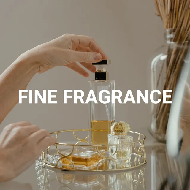 Main tenant un flacon de parfum élégant sur plateau doré - ingrédients naturels pour parfumerie fine